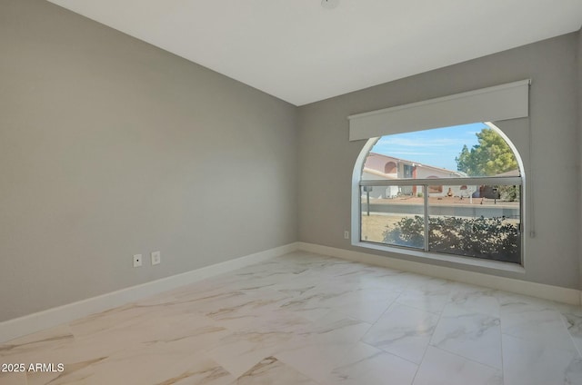 empty room featuring marble finish floor and baseboards
