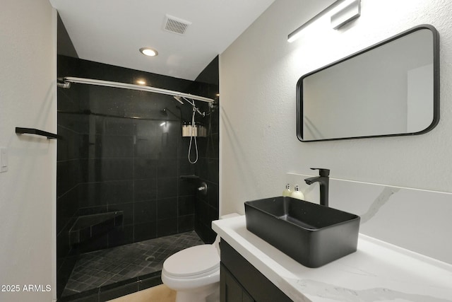 full bath featuring visible vents, vanity, a shower stall, and toilet