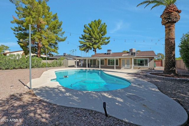 view of pool featuring a storage shed, a fenced backyard, a fenced in pool, and a patio