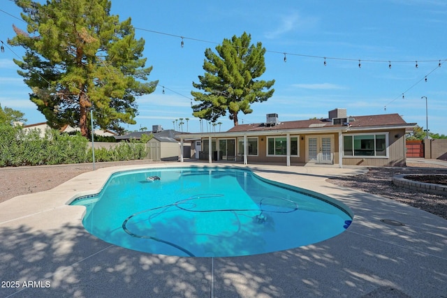 view of pool featuring a fenced backyard, a storage shed, an outdoor structure, french doors, and a fenced in pool
