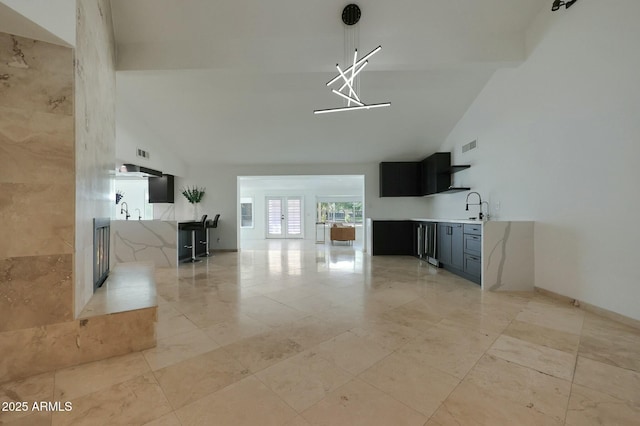unfurnished living room featuring baseboards, visible vents, french doors, high vaulted ceiling, and a sink