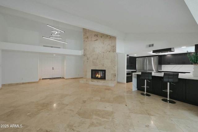 unfurnished living room featuring high vaulted ceiling, baseboards, a fireplace, and visible vents