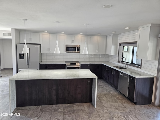 kitchen featuring pendant lighting, sink, a kitchen island, and appliances with stainless steel finishes