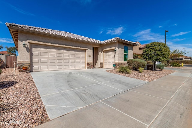 view of front facade featuring driveway, stone siding, an attached garage, and stucco siding