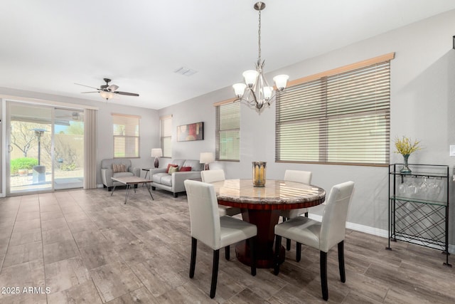 dining space with baseboards, visible vents, wood finished floors, and ceiling fan with notable chandelier