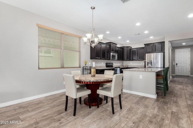 dining area with a chandelier, recessed lighting, light wood-style flooring, and baseboards