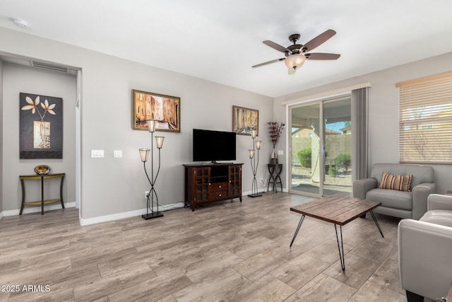 living room with light wood-style floors, baseboards, visible vents, and a ceiling fan