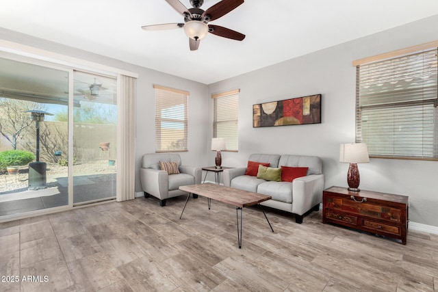 living room with ceiling fan, light wood finished floors, and baseboards