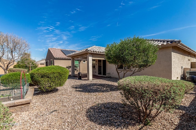 back of property featuring a tile roof, a vegetable garden, a patio, and stucco siding