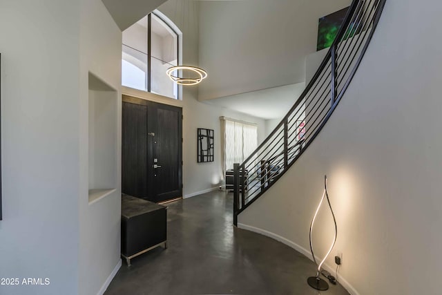 foyer with stairway, a healthy amount of sunlight, finished concrete flooring, and baseboards