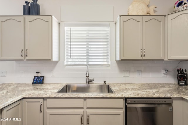 kitchen featuring decorative backsplash, stainless steel dishwasher, light stone countertops, and sink