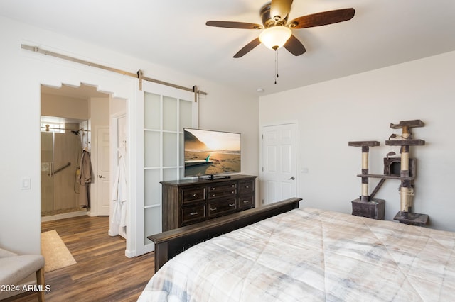 bedroom featuring ceiling fan, a barn door, dark hardwood / wood-style flooring, and ensuite bath