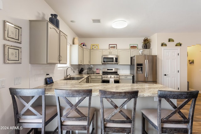 kitchen with backsplash, sink, a breakfast bar area, and stainless steel appliances