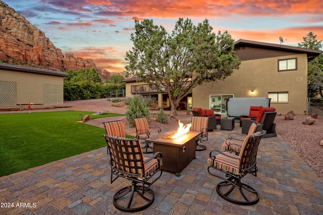 patio terrace at dusk featuring an outdoor living space with a fire pit and a lawn