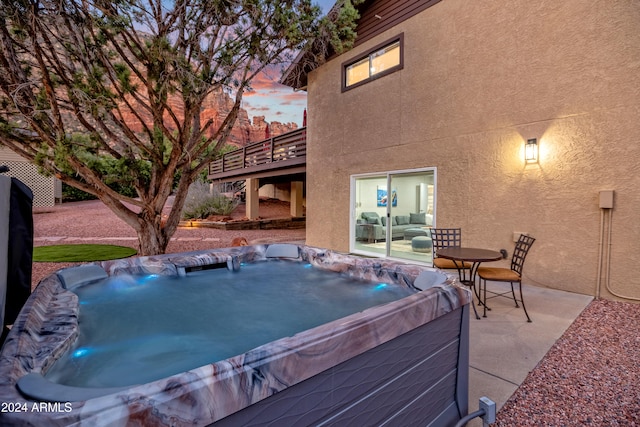 patio terrace at dusk featuring a hot tub