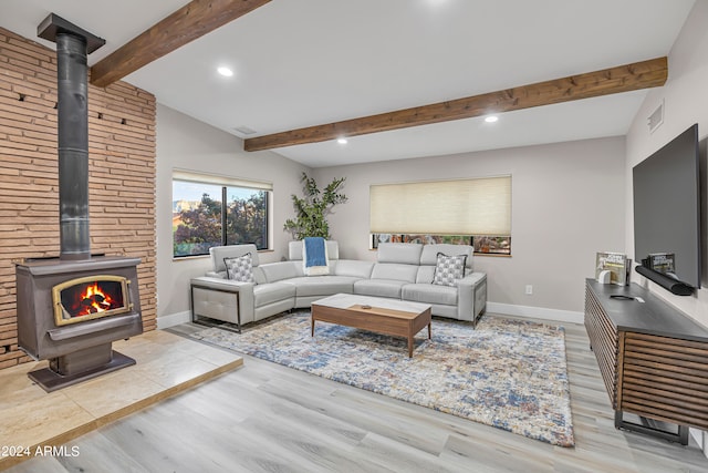 living room featuring vaulted ceiling with beams, light hardwood / wood-style flooring, and a wood stove