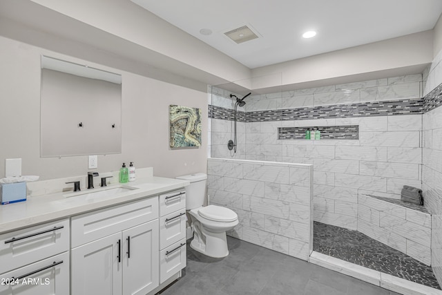 bathroom featuring vanity, tile patterned floors, toilet, and tiled shower