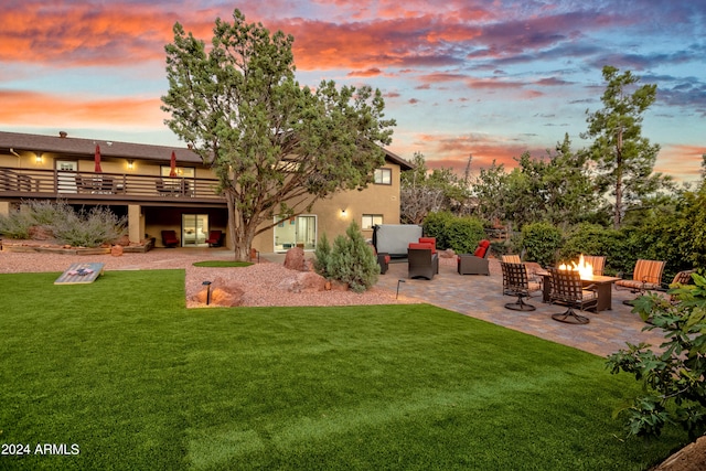 yard at dusk featuring a patio and an outdoor living space with a fire pit