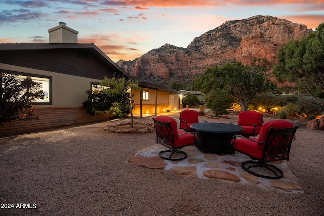 patio terrace at dusk featuring a mountain view and an outdoor fire pit