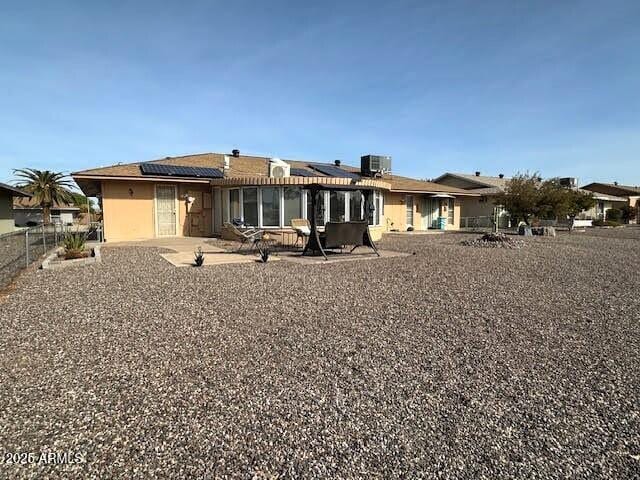 back of property with a patio and solar panels