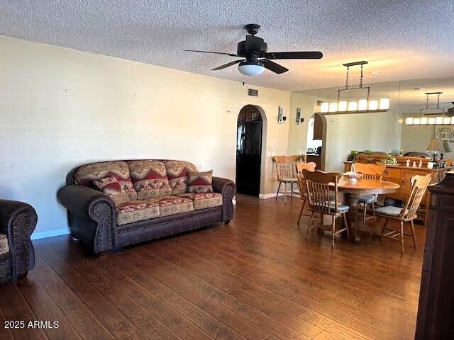 living room with ceiling fan, dark hardwood / wood-style floors, and a textured ceiling