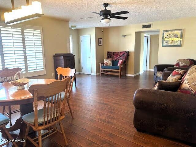 living room featuring ceiling fan, dark wood-type flooring, and a textured ceiling