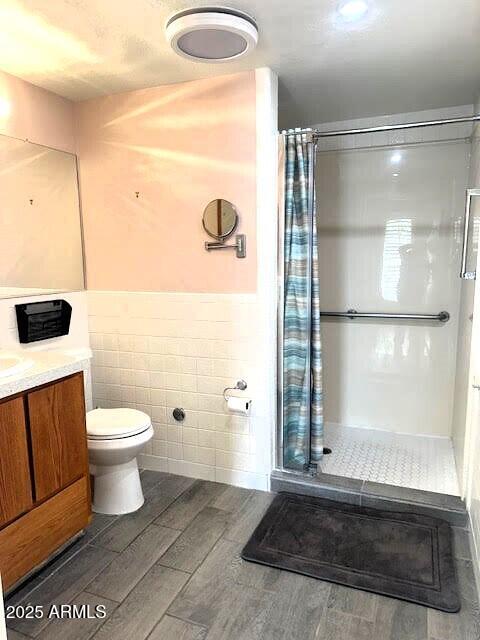 bathroom with tile walls, vanity, a shower with curtain, and toilet