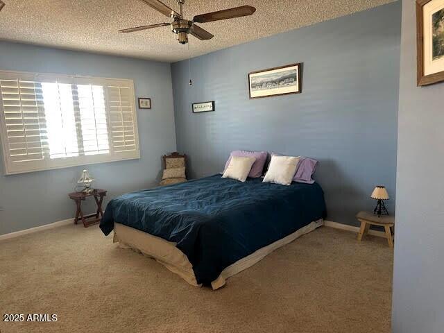 carpeted bedroom featuring ceiling fan and a textured ceiling