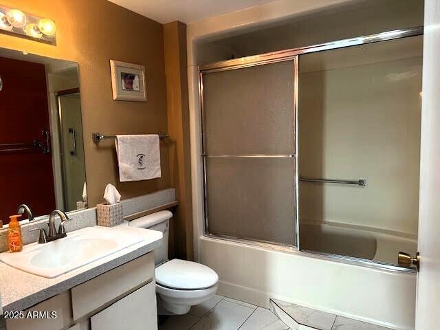 full bathroom with bath / shower combo with glass door, vanity, tile patterned floors, and toilet