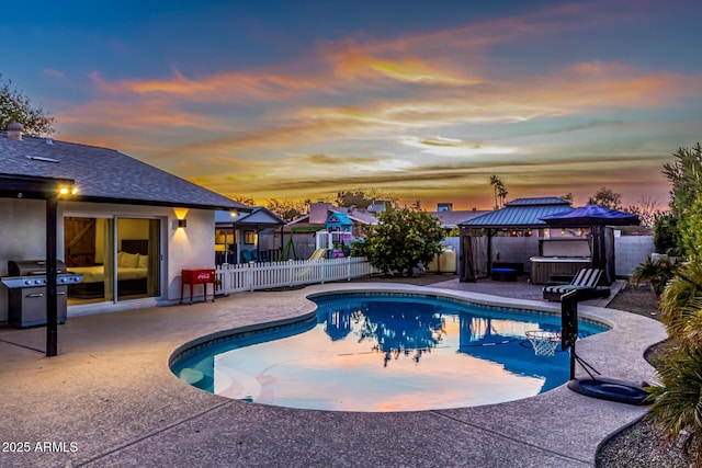 pool at dusk featuring a hot tub, a gazebo, grilling area, and a patio area