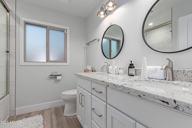 full bathroom featuring wood-type flooring, toilet, vanity, and bath / shower combo with glass door