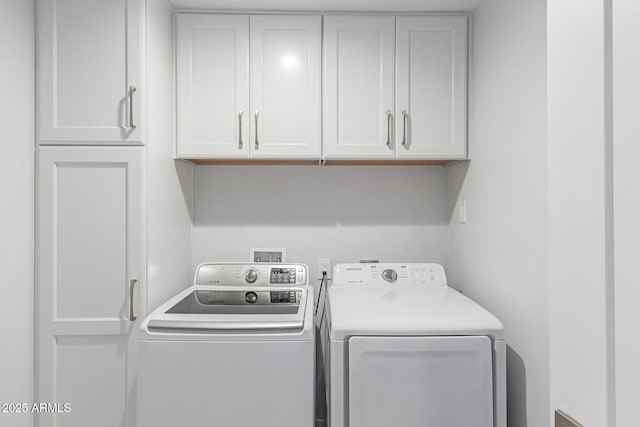 laundry room featuring washer and clothes dryer and cabinets