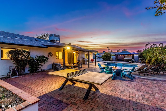 pool at dusk with a gazebo, central AC, and a patio