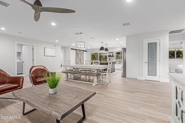 living room with ceiling fan, washer / clothes dryer, and light hardwood / wood-style flooring