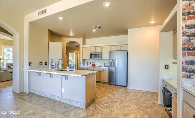 kitchen featuring appliances with stainless steel finishes, light tile floors, sink, and light stone countertops