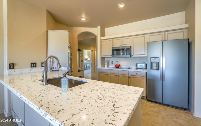 kitchen featuring sink, light tile floors, stainless steel appliances, and light stone countertops