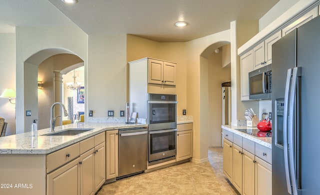 kitchen featuring sink, light tile flooring, stainless steel appliances, and light stone countertops