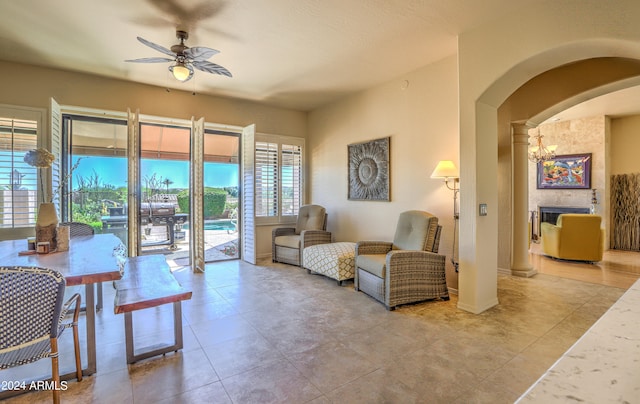 tiled living room featuring a fireplace and ceiling fan