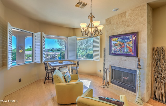 interior space featuring a healthy amount of sunlight, a fireplace, an inviting chandelier, and light wood-type flooring