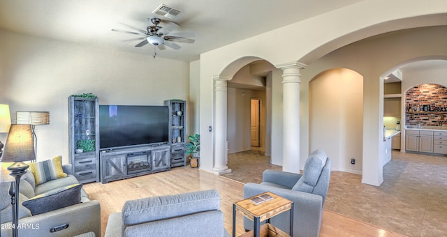 tiled living room featuring ornate columns and ceiling fan