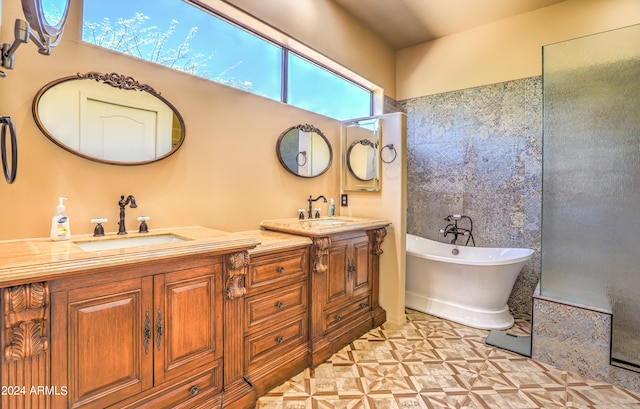 bathroom with double vanity, a bath to relax in, a healthy amount of sunlight, and tile floors