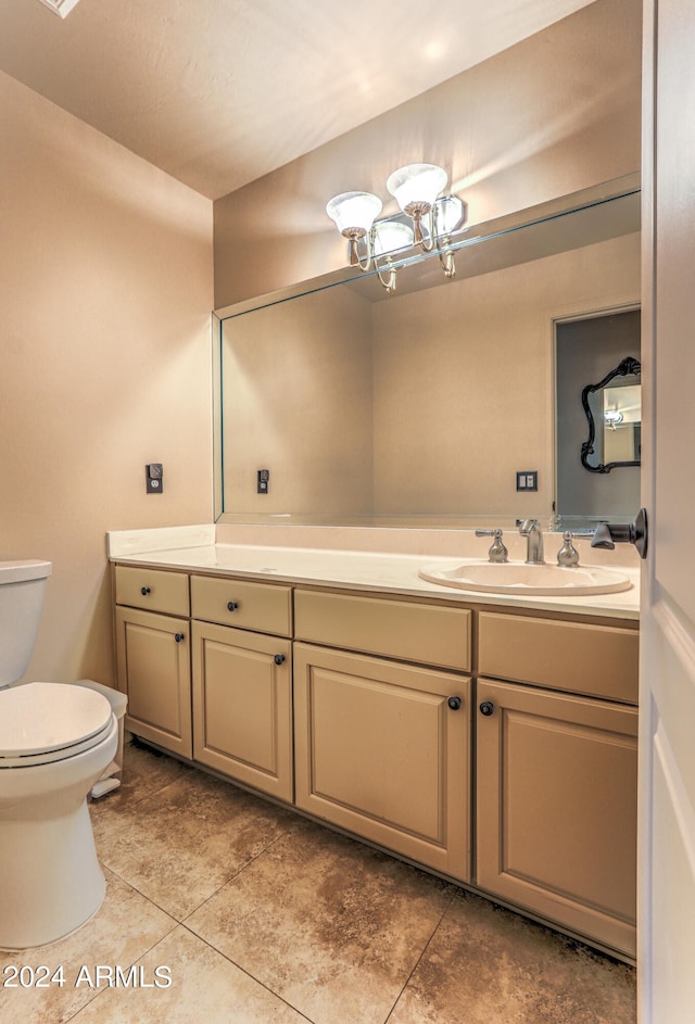 bathroom with tile floors, vanity, toilet, and an inviting chandelier