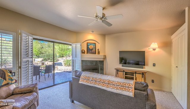 carpeted living room with ceiling fan and a fireplace