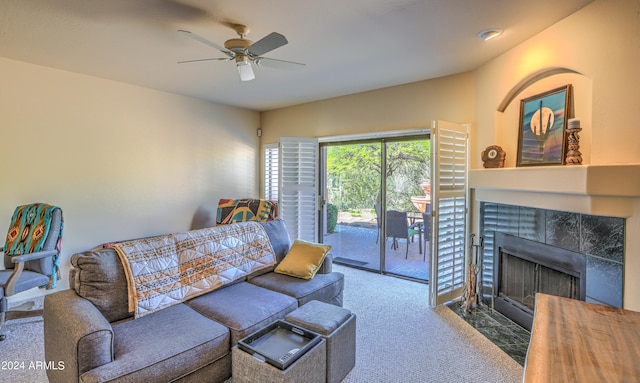 living room featuring dark colored carpet, a tile fireplace, and ceiling fan