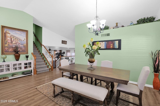 dining space with lofted ceiling, hardwood / wood-style flooring, and an inviting chandelier