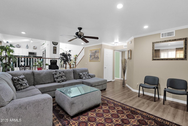 living room with hardwood / wood-style flooring, ceiling fan, and ornamental molding