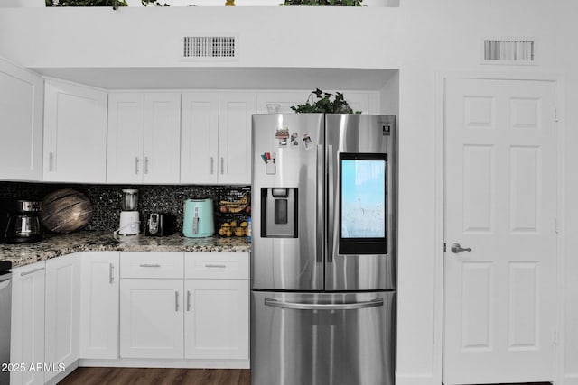 kitchen featuring decorative backsplash, stainless steel fridge, white cabinets, and stone countertops