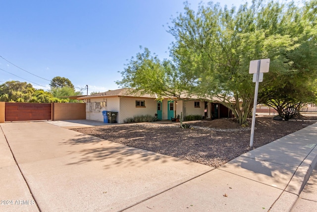 single story home with concrete driveway, a gate, and fence