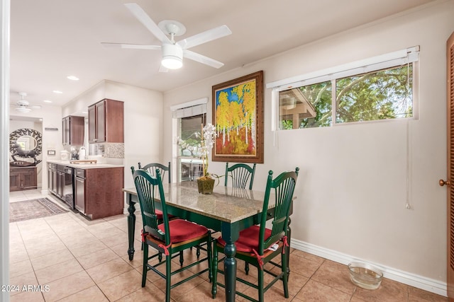 dining room with baseboards, a ceiling fan, light tile patterned flooring, and a healthy amount of sunlight