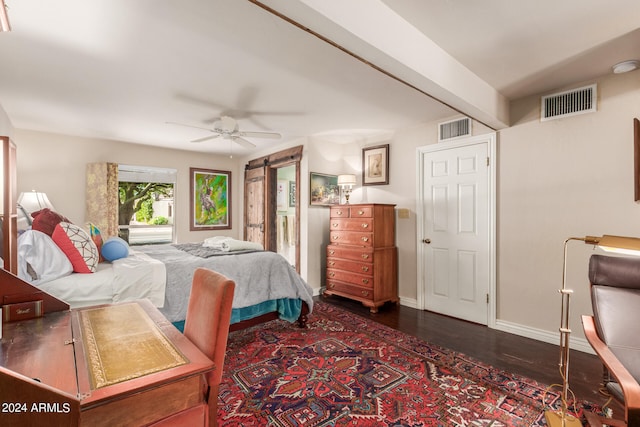 bedroom with a barn door, dark hardwood / wood-style floors, beamed ceiling, and ceiling fan